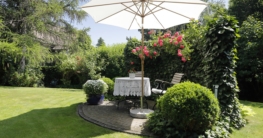 Idyllischer Sitzplatz im Garten mit Sonnenschirm