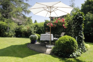 Idyllischer Sitzplatz im Garten mit Sonnenschirm